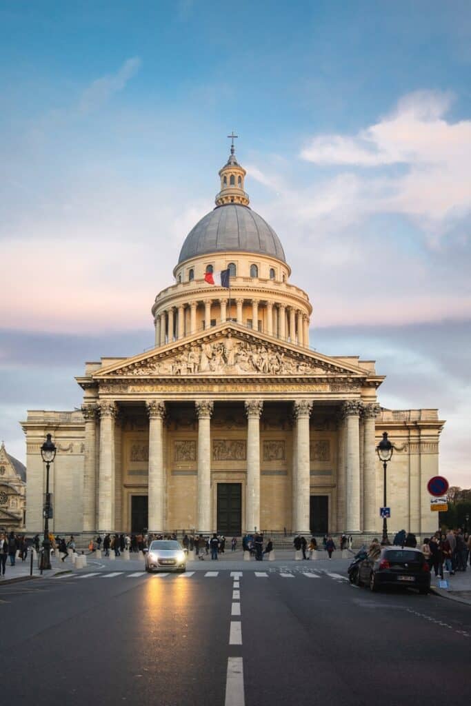 Pantheon surrounded by people under a cloudy sky during sunset in Paris in France