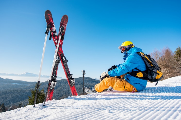 skieur avec son matériel de ski assis sur la montagne